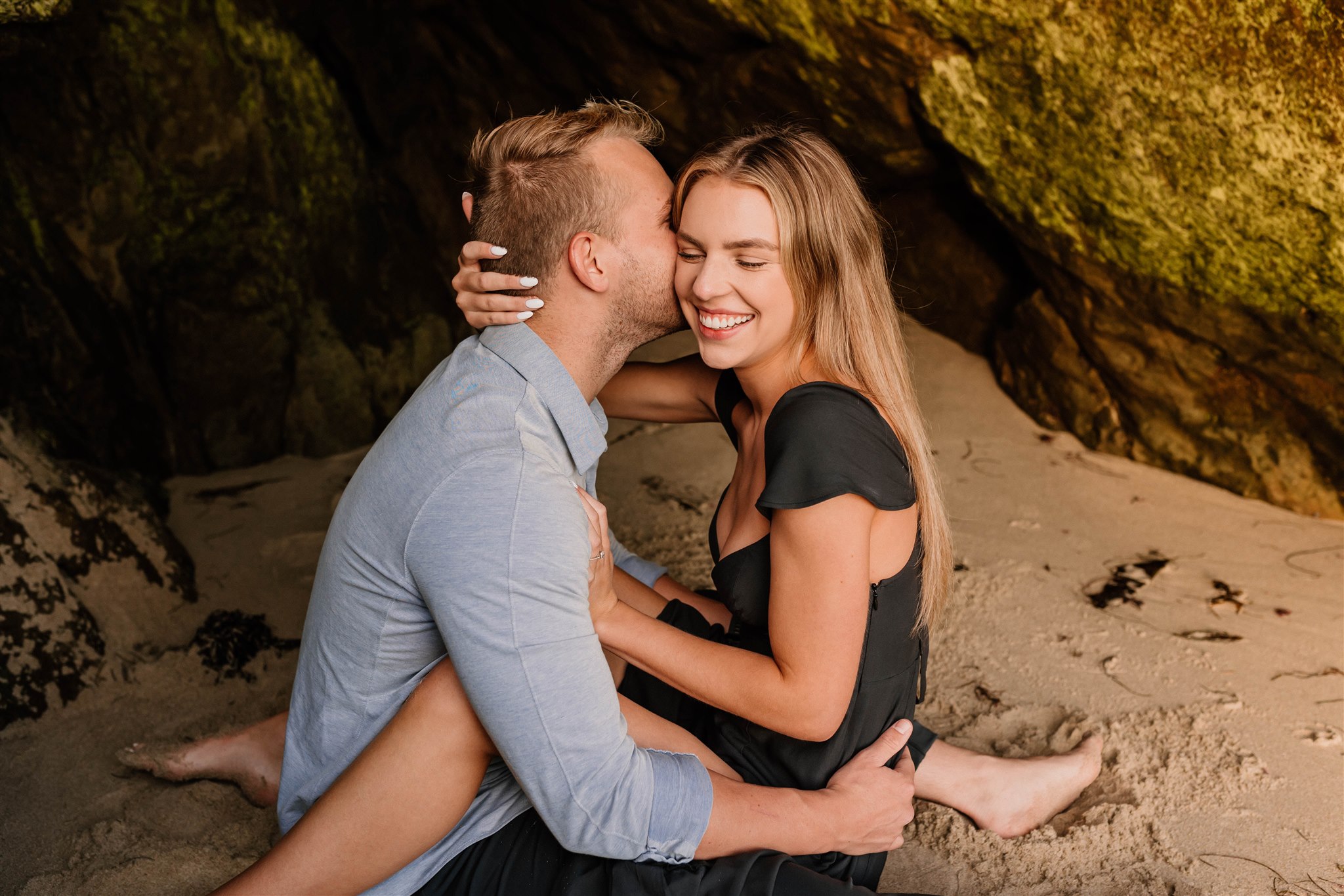 couple laughing in a cave on the beach