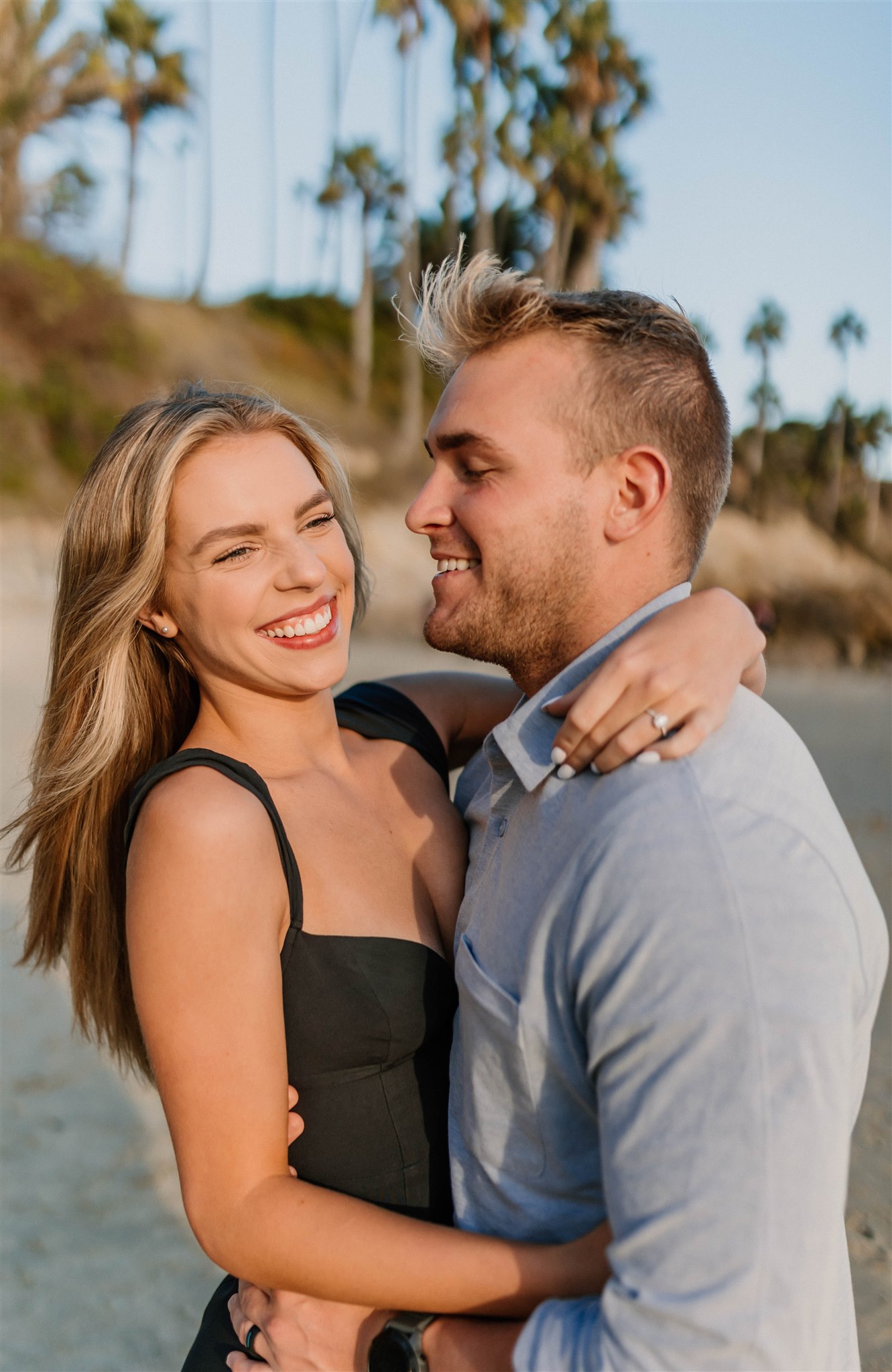 couple laughing and posing on a beach