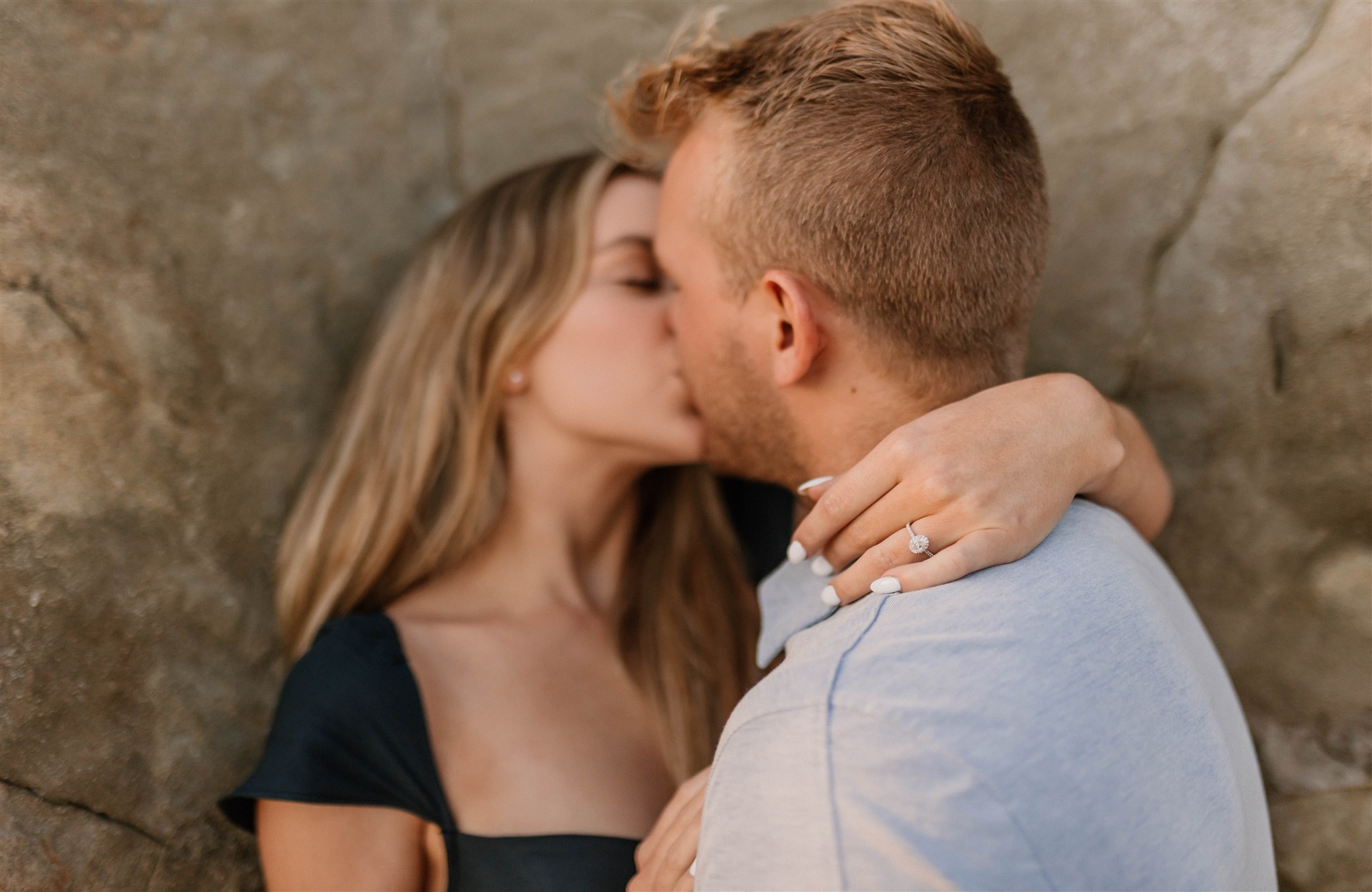 couple leaning against a rock and kissing