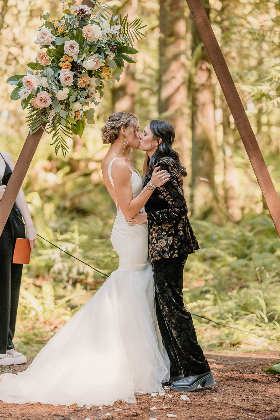 married couple sharing their first kiss in the forest during their ceremony
