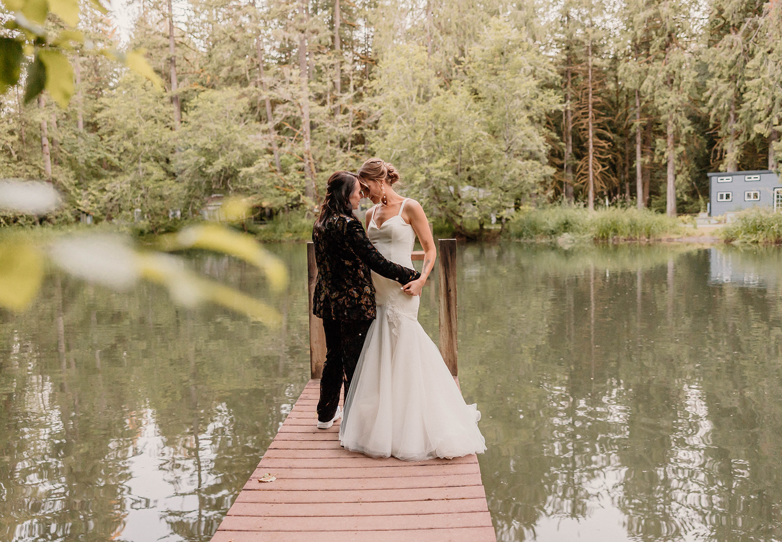 married couple posing on a dock near a lake
