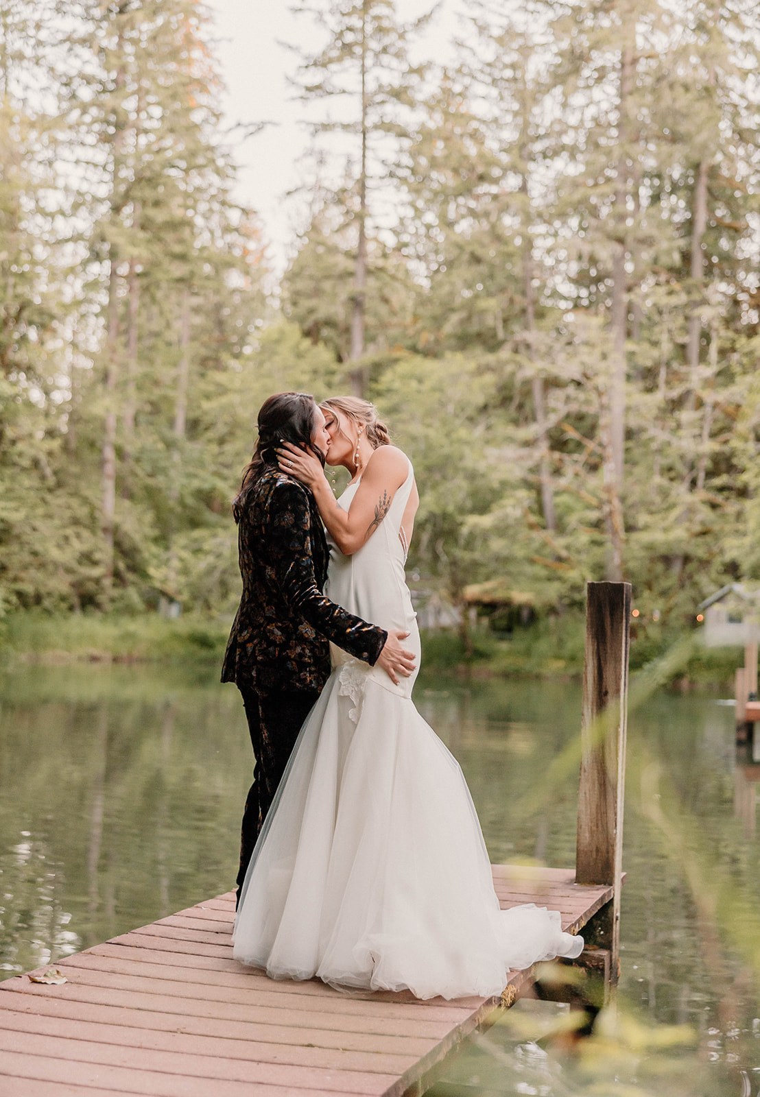 married couple posing and kissing on a dock near a lake