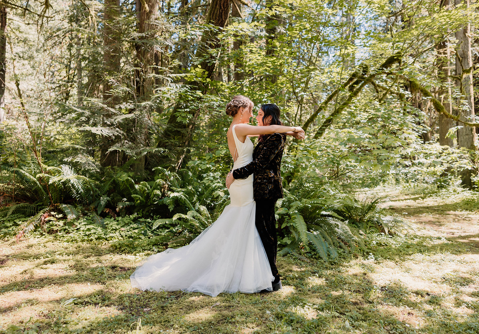 married couple posing and smiling in a forest