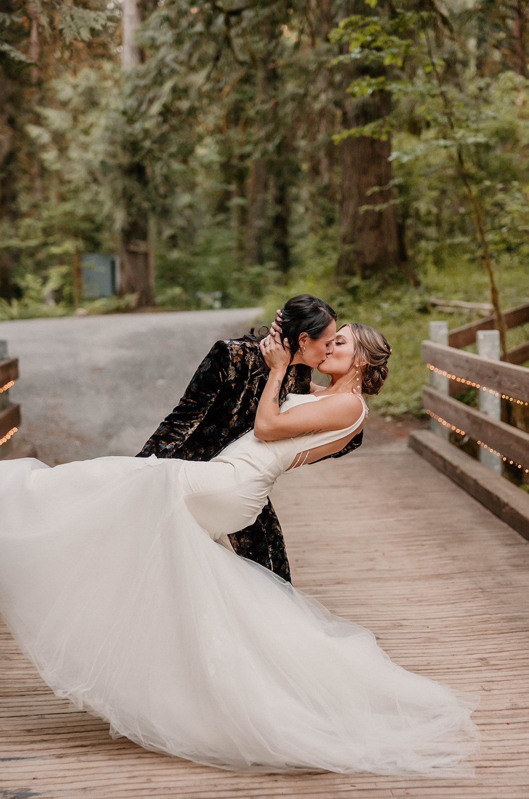 married couple kissing and posing on a bridge