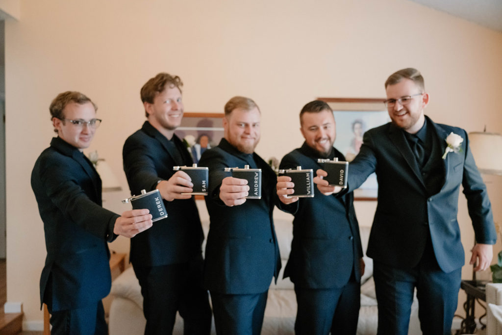 groom and groomsmen holding custom wedding flasks
