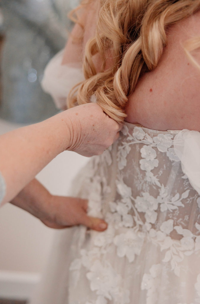 Bride getting her wedding dress zipped