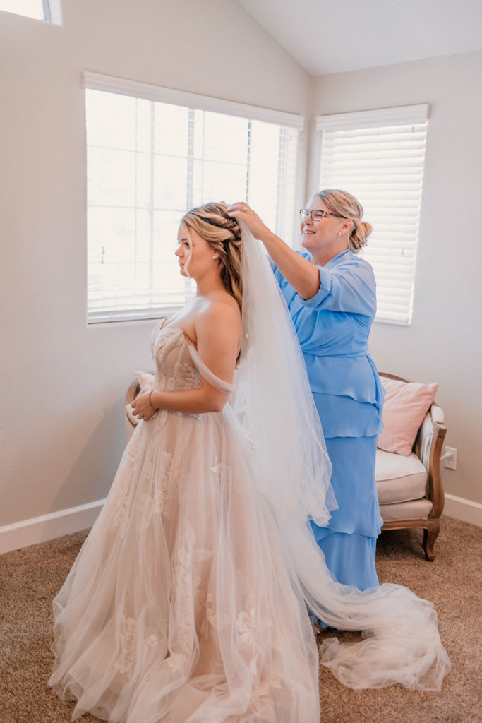 Brides mother putting on brides wedding veil