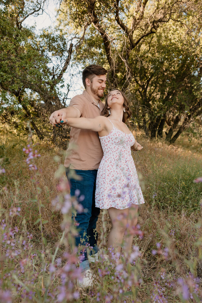 Couple posing for photos at Folsom Lake for a wildflower couples photoshoot 