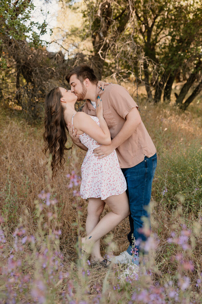 Couple posing for photos at Folsom Lake for a wildflower couples photoshoot 