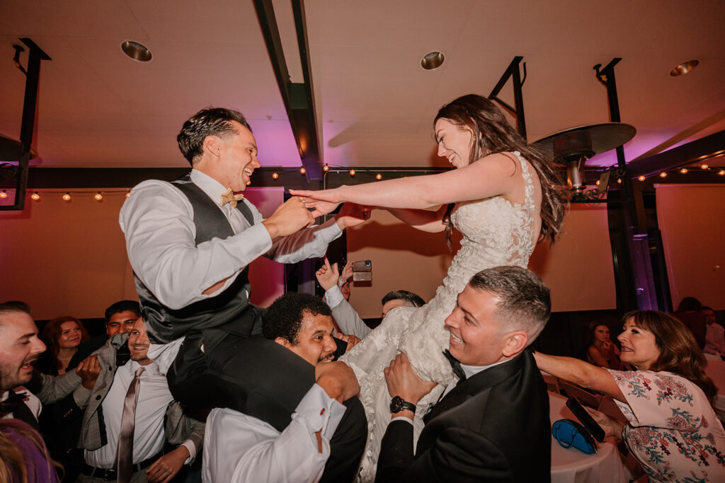Bride and groom being lifted in the air during wedding reception