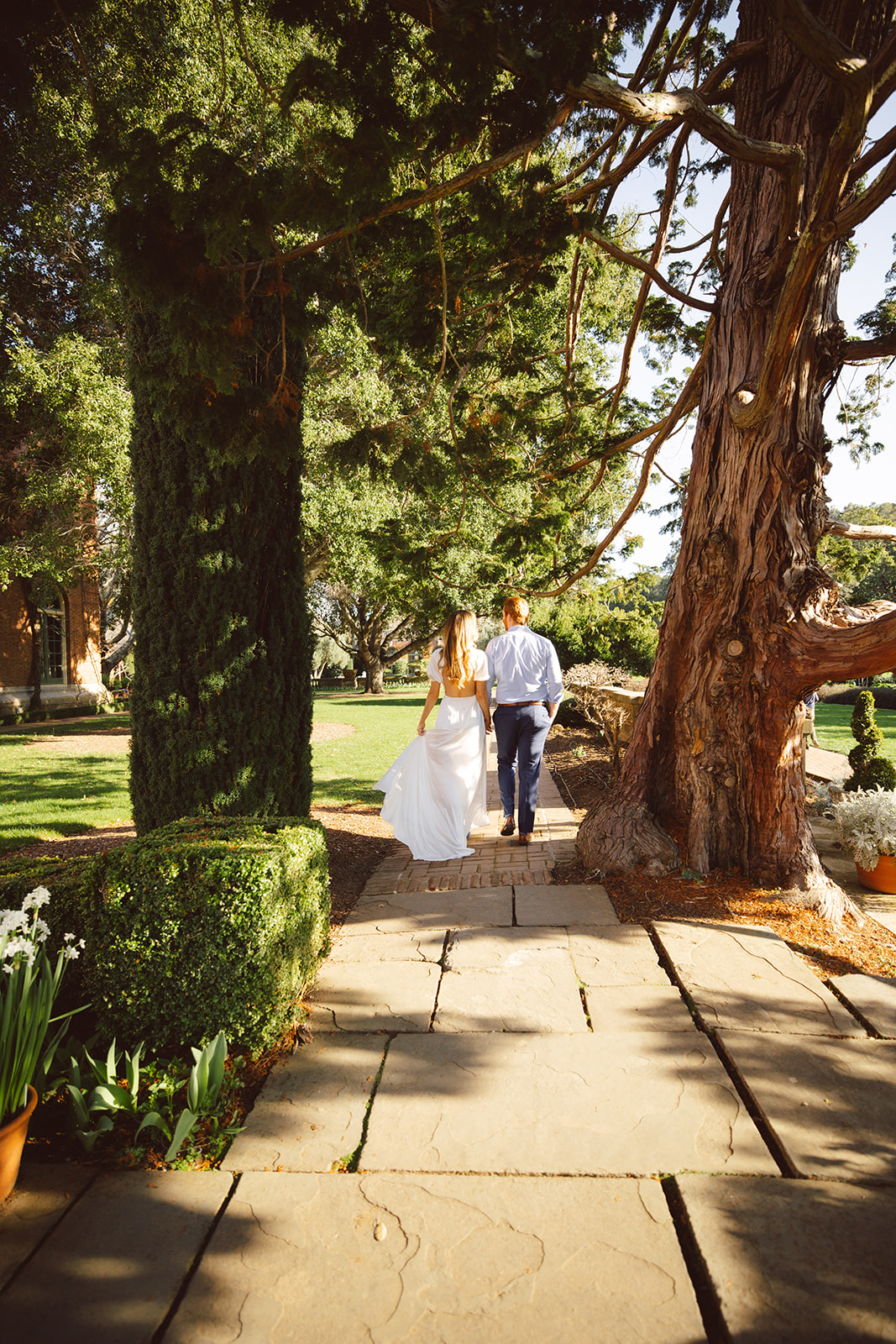 A couple embracing and smiling at Filoli Gardens, taking their engagement photos, both dressed in casual attire.