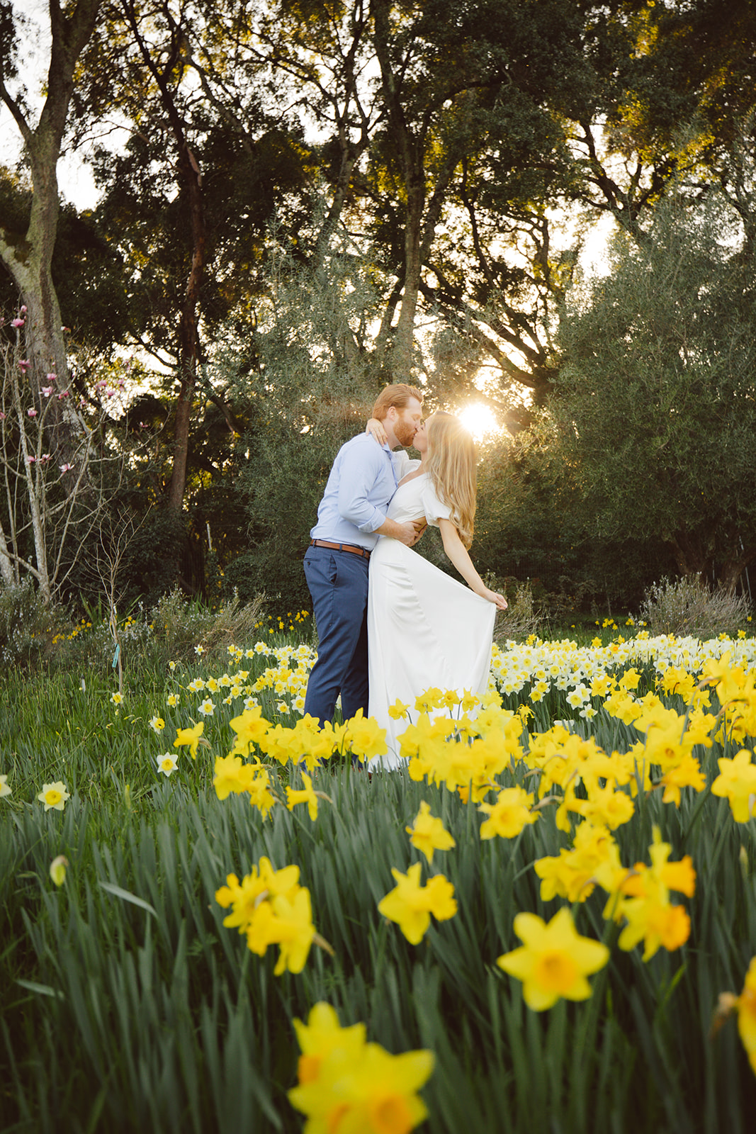 A couple embracing and smiling at Filoli Gardens, taking their engagement photos, both dressed in casual attire.