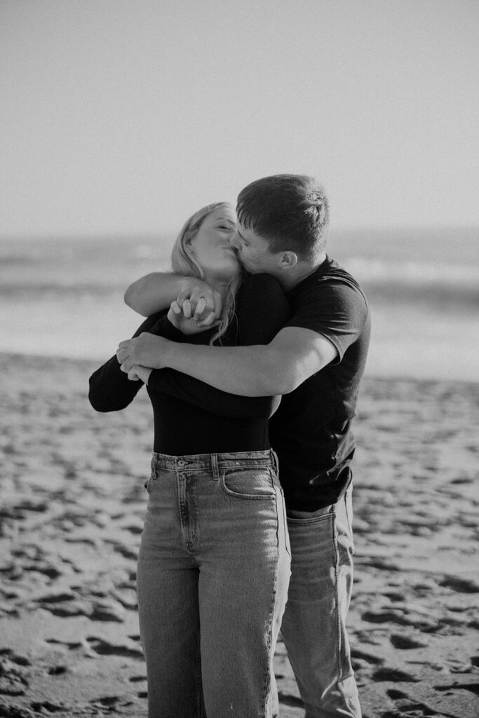 a couple posing for their proposal photos on the beach
