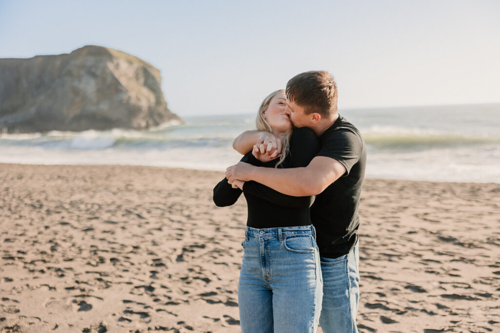 a couple posing for their proposal photos on the beach
