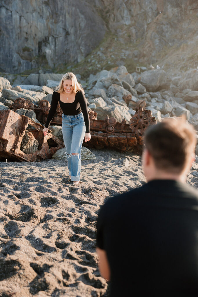 a couple posing for their proposal photos on the beach
