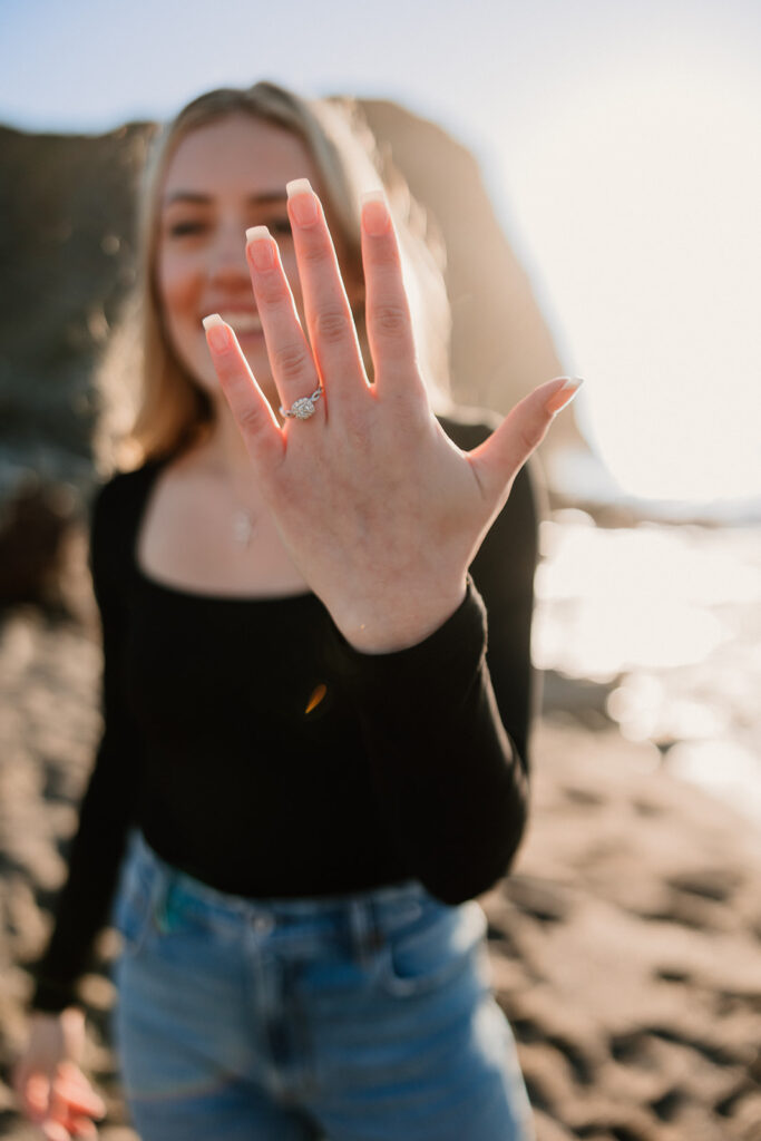 a couple posing for their proposal photos on the beach
