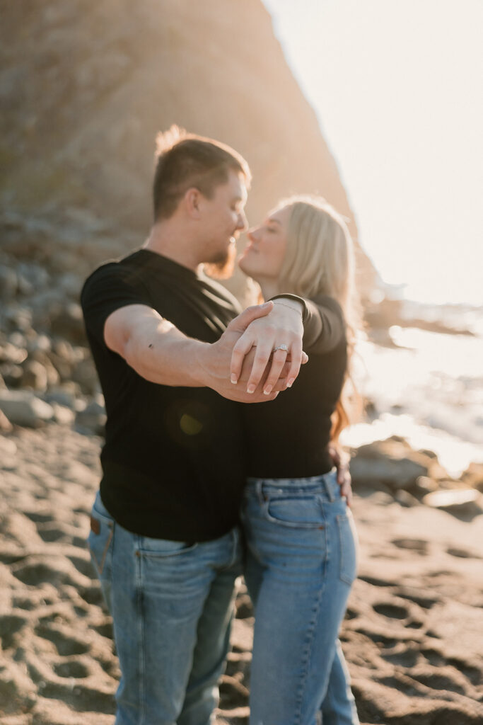 a couple posing for their proposal photos on the beach
