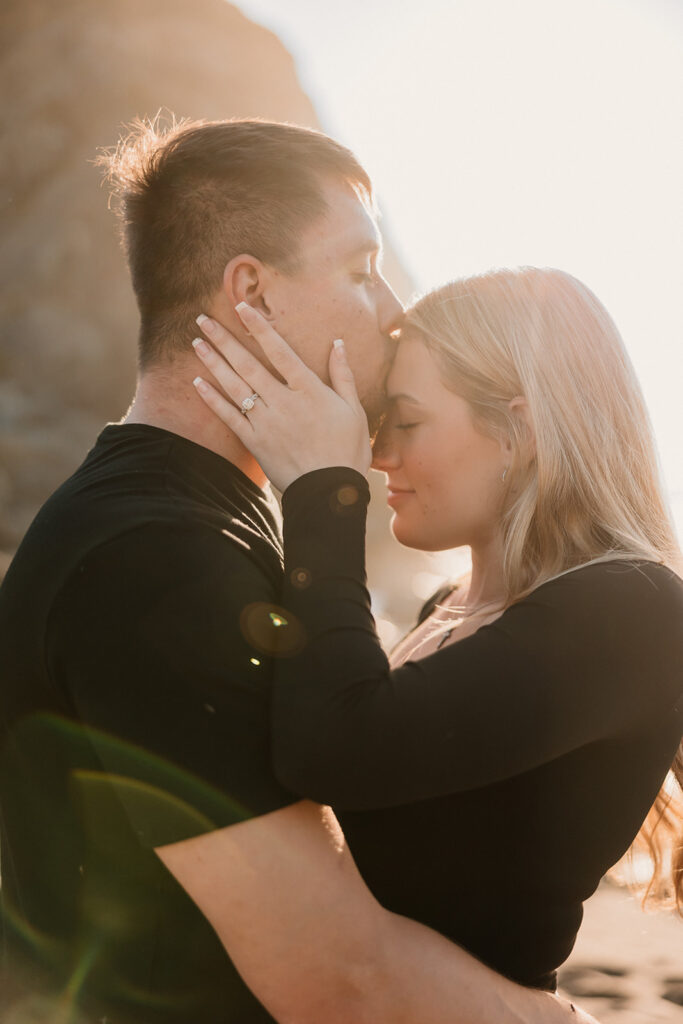 a couple posing for their proposal photos on the beach
