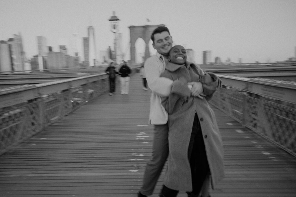 couple taking photos on the brooklyn bridge
