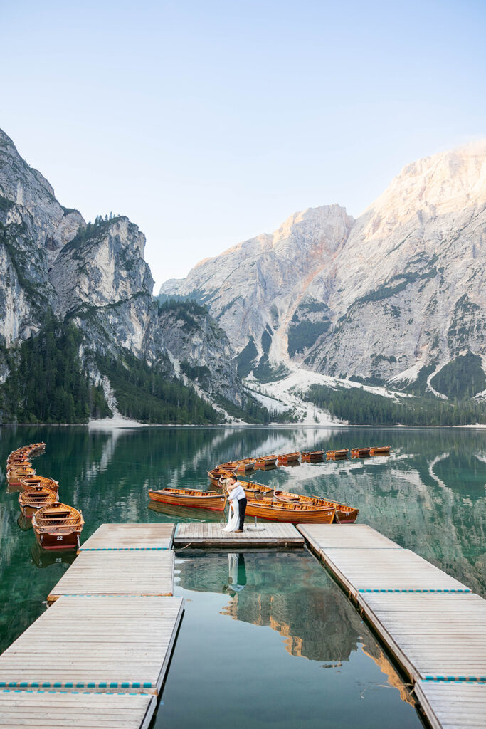 A pair enjoying their elopement photoshoot in the stunning setting of Lago di Braies, surrounded by the Dolomites in Italy.
