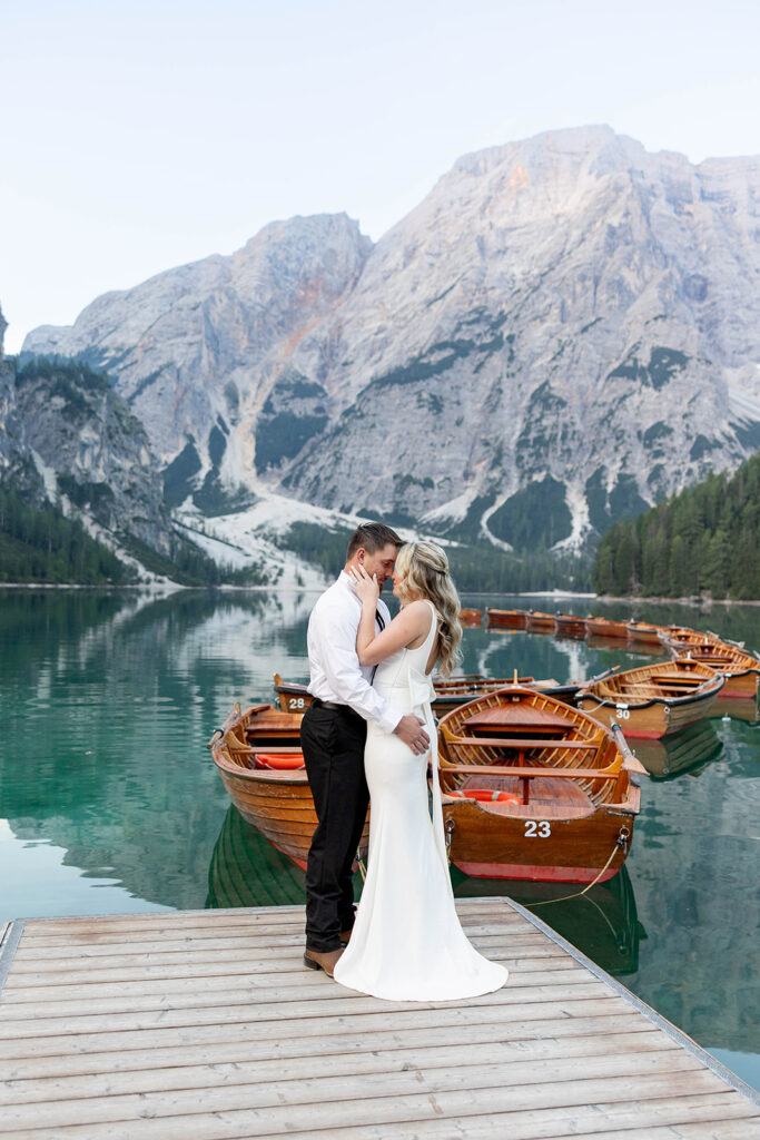 A couple capturing their special elopement moments by the serene waters of Lago di Braies in Italy’s Dolomites
