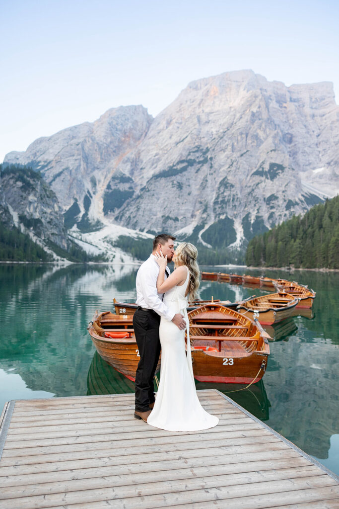 A couple capturing their special elopement moments by the serene waters of Lago di Braies in Italy’s Dolomites
