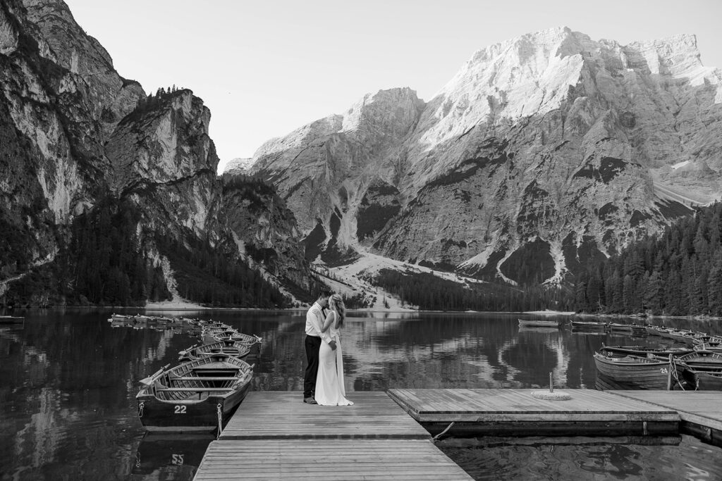 A couple capturing their special elopement moments by the serene waters of Lago di Braies in Italy’s Dolomites
