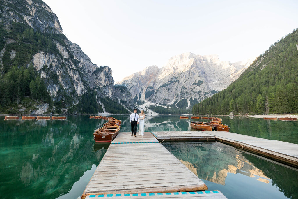 A couple capturing their special elopement moments by the serene waters of Lago di Braies in Italy’s Dolomites
