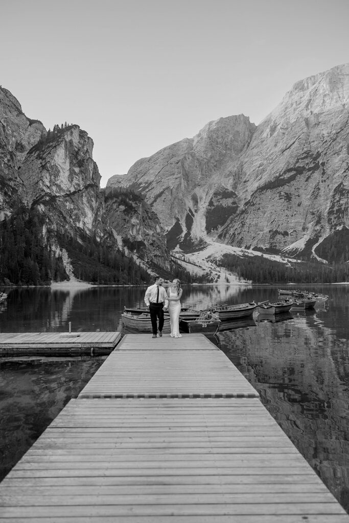 A couple capturing their special elopement moments by the serene waters of Lago di Braies in Italy’s Dolomites