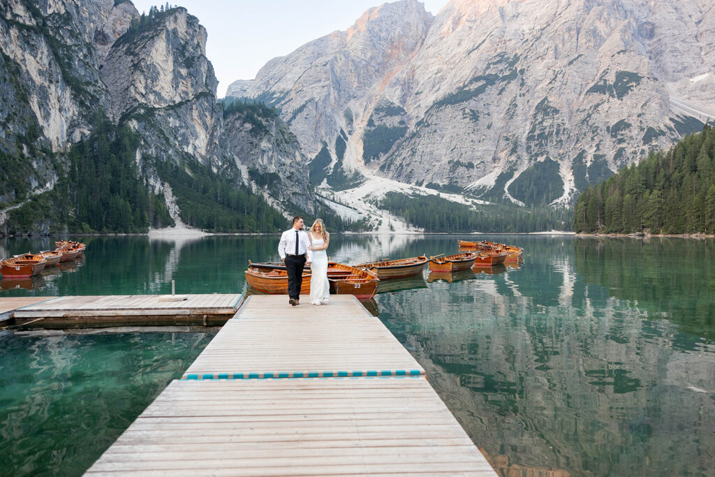 A couple capturing their special elopement moments by the serene waters of Lago di Braies in Italy’s Dolomites
