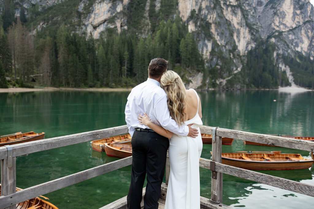 Two people posing by the picturesque Lago di Braies in the Dolomites for their destination elopement photos.
