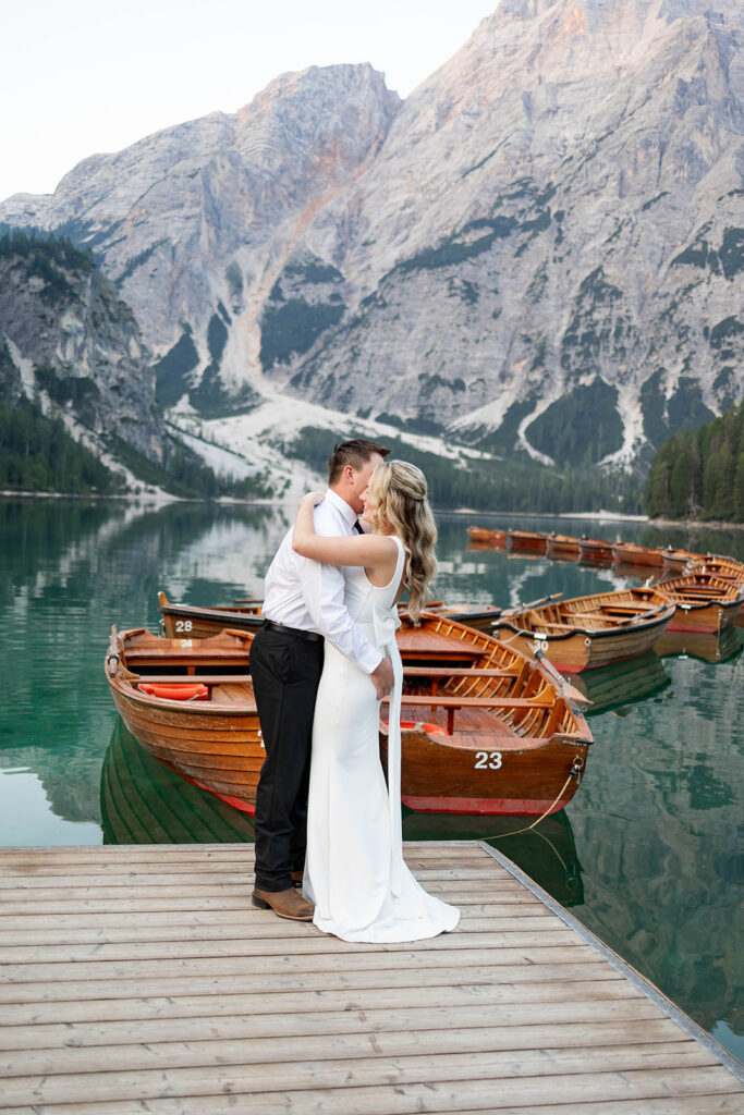 Two people posing by the picturesque Lago di Braies in the Dolomites for their destination elopement photos.
