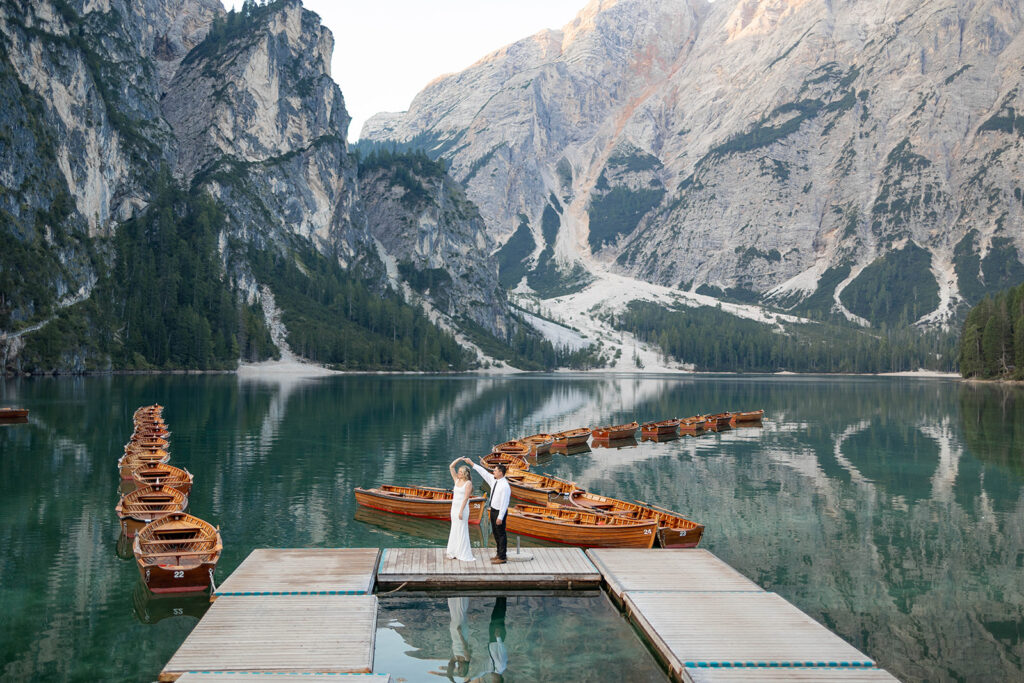 A pair enjoying their elopement photoshoot in the stunning setting of Lago di Braies, surrounded by the Dolomites in Italy.
