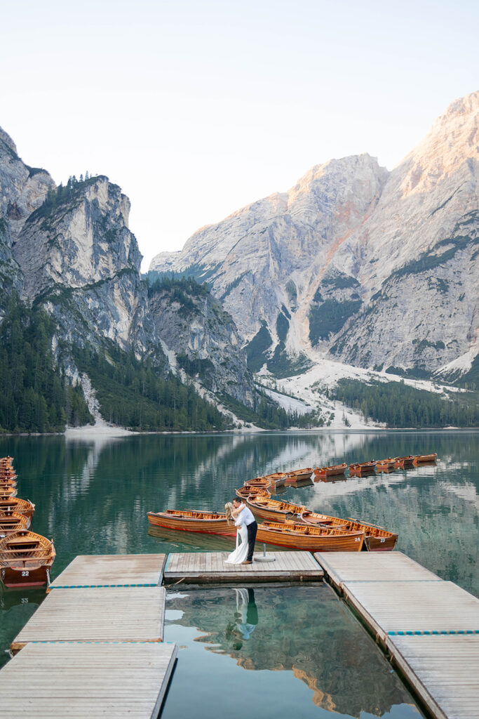 A pair enjoying their elopement photoshoot in the stunning setting of Lago di Braies, surrounded by the Dolomites in Italy.
