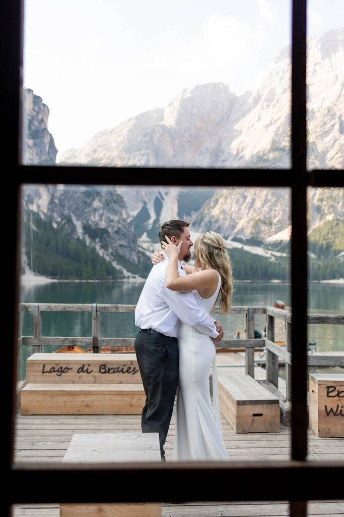 A couple capturing their special elopement moments by the serene waters of Lago di Braies in Italy’s Dolomites
