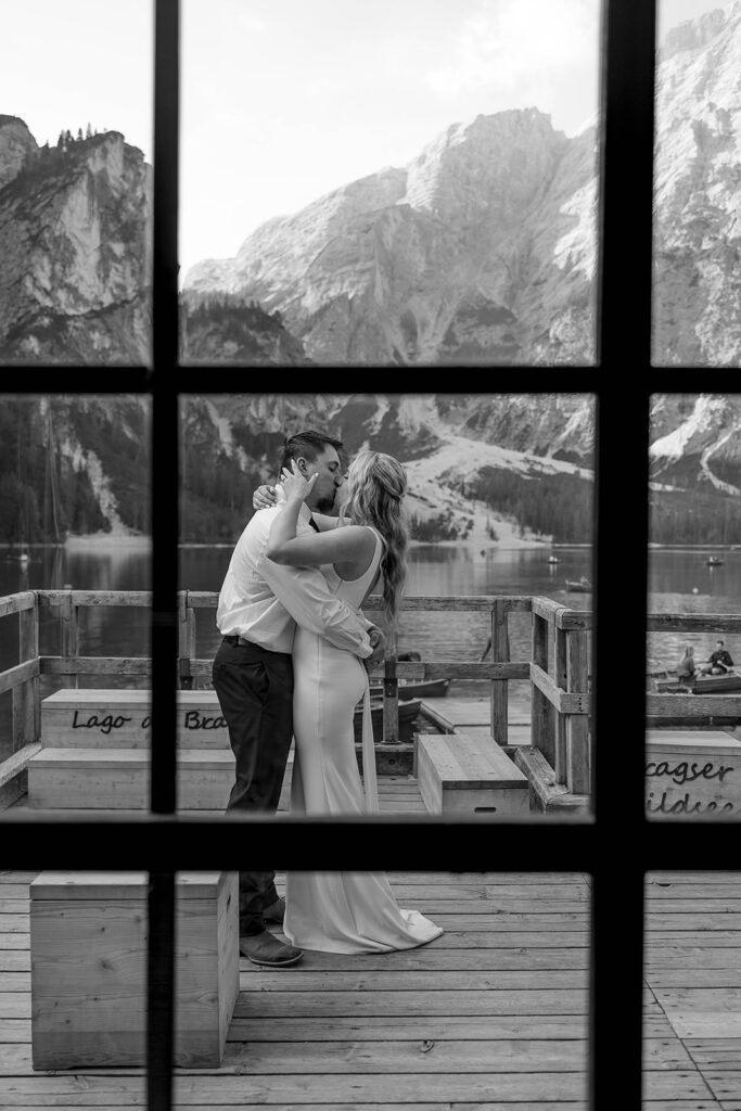 A couple capturing their special elopement moments by the serene waters of Lago di Braies in Italy’s Dolomites
