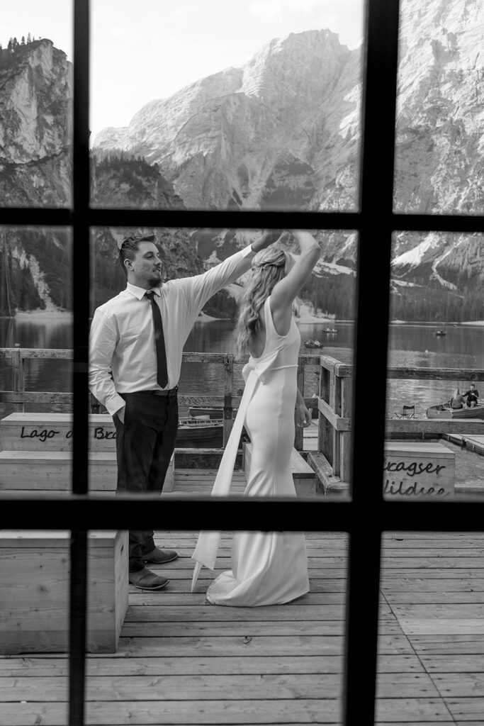 A couple capturing their special elopement moments by the serene waters of Lago di Braies in Italy’s Dolomites
