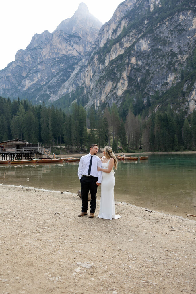 Two people posing by the picturesque Lago di Braies in the Dolomites for their destination elopement photos.
