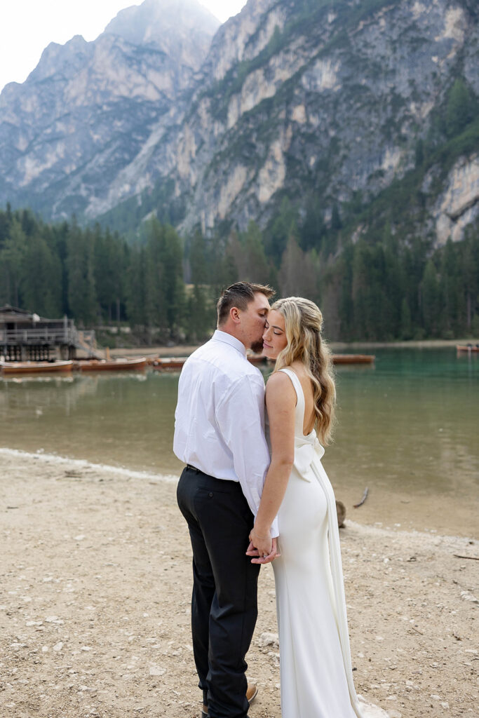 Two people posing by the picturesque Lago di Braies in the Dolomites for their destination elopement photos.
