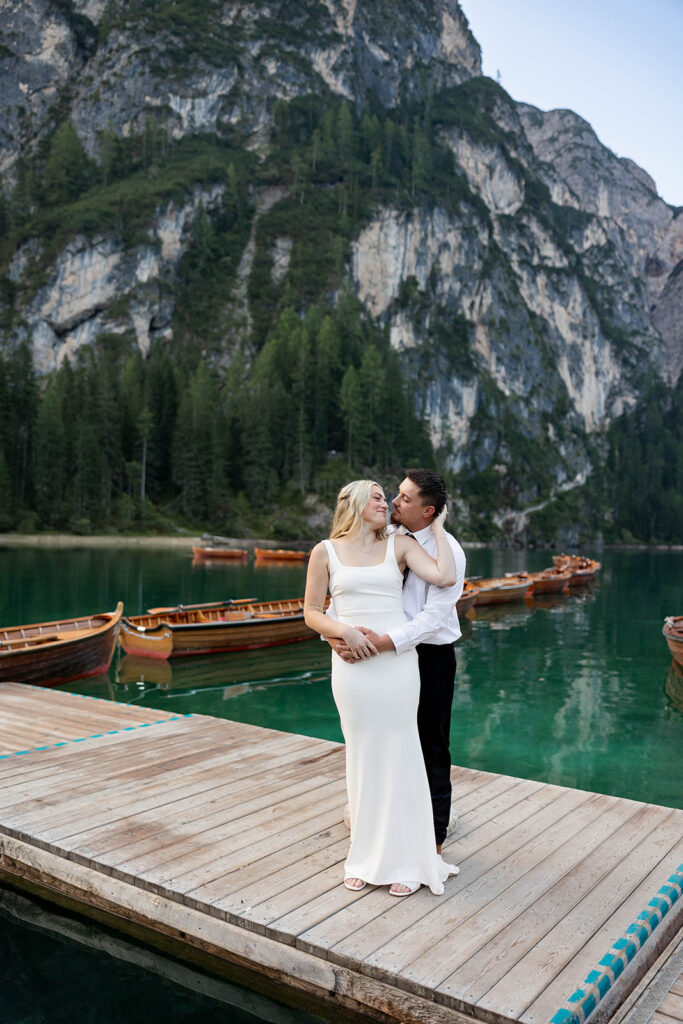 Two people posing by the picturesque Lago di Braies in the Dolomites for their destination elopement photos.
