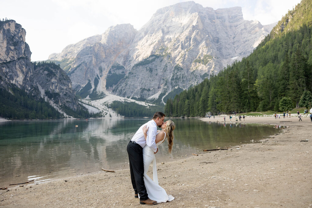 Two people posing by the picturesque Lago di Braies in the Dolomites for their destination elopement photos.
