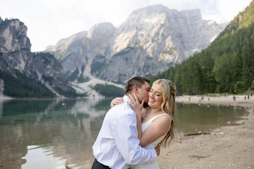 Two people posing by the picturesque Lago di Braies in the Dolomites for their destination elopement photos.
