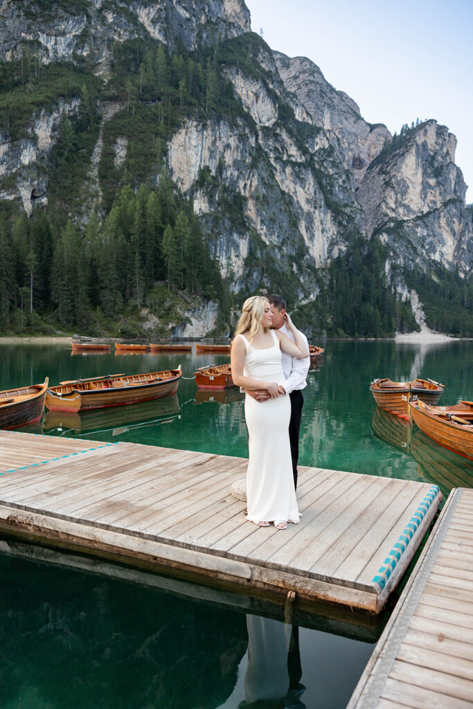 Two people posing by the picturesque Lago di Braies in the Dolomites for their destination elopement photos.
