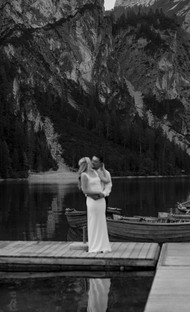 Two people posing by the picturesque Lago di Braies in the Dolomites for their destination elopement photos.
