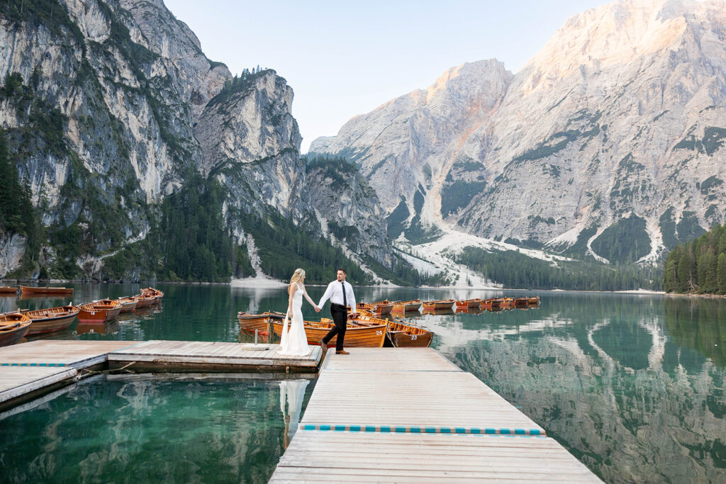 Two people posing by the picturesque Lago di Braies in the Dolomites for their destination elopement photos.
